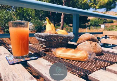 a glass of orange juice sitting on a picnic table with bread at Apartment Sant'Ana Old Town Albufeira - Bay View in Albufeira