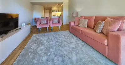 a living room with a couch and pink chairs at Victory Village 18E in Quinta do Lago