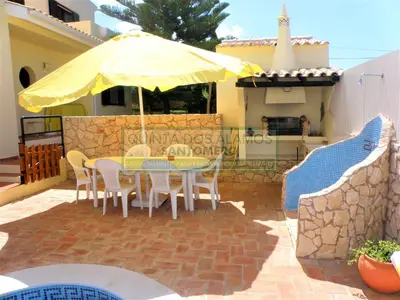 a patio with a table and chairs and an umbrella at Villa Catuna - Quinta do Jolu in Guia