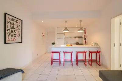 a kitchen with red bar stools and a counter at Modern Apartment by the Sea in Quarteira