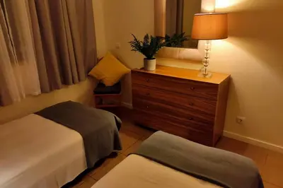 a room with two beds and a dresser with a lamp at Varandas Golden Beach in Quarteira