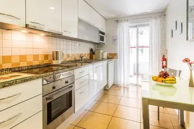 a kitchen with white cabinets and a bowl of fruit on a counter at Varandas Golden Beach in Quarteira