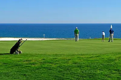 a group of people playing golf near the ocean at Casa Vale Do Lobo 32 Charming 2 Bedroom Townhouse Close To Beach in Vale do Lobo