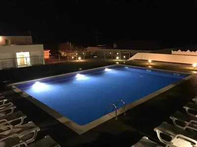 a large blue swimming pool with chairs at night at 
