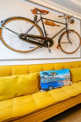 a bike hanging on the wall above a yellow couch at Casinha da Ti Babel in Faro