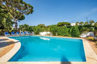 a swimming pool with blue chairs and trees at Villa Quadradinhos 38Q 4 Bedrooms Private Pool Short Walk To The Beach in Vale do Lobo