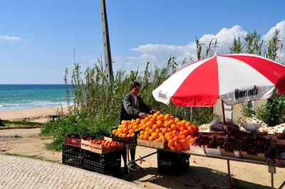 a man standing next to a fruit stand with an umbrella at Villa Quadradinhos 21Q 4 Bedroooms Private Pool Vale Do Lobo in Vale do Lobo