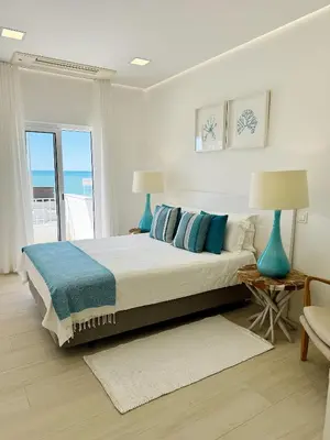 a bedroom with a bed with blue lamps and a window at Seafront Apartment in Quarteira in Quarteira