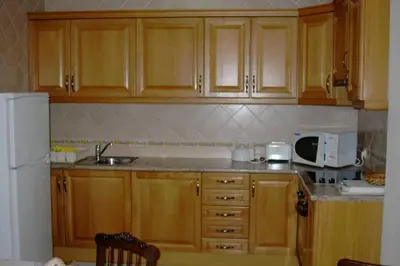 a kitchen with wooden cabinets and a white refrigerator at Casa do Avô in Albufeira