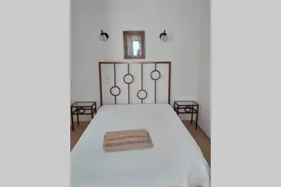 a bedroom with a white bed with a metal headboard at Casa do Avô in Albufeira