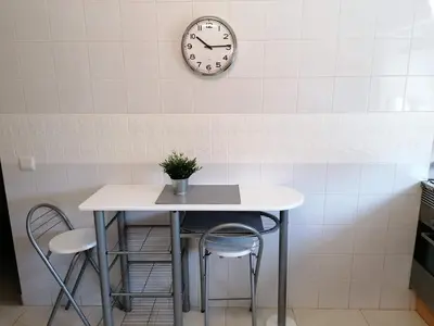 a table and two chairs and a clock on a wall at Bel Appartement 2 chambres au cœur d’Albufeira, proche de la magnifique plage de Oura et des loisirs in Albufeira