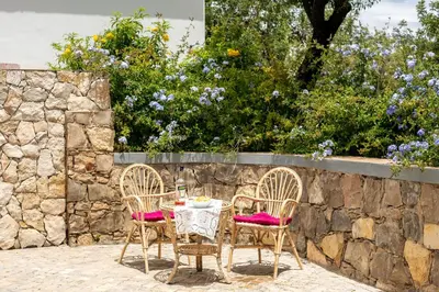 a table and chairs in front of a stone wall at Villa Rodrigues in Boliqueime
