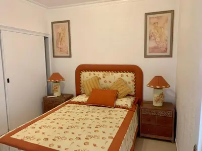 a bedroom with a bed with two night stands and two lamps at Apartamento Frente praia in Quarteira