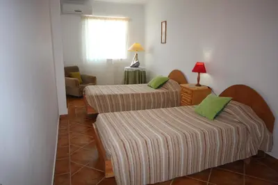 a hotel room with two beds and a chair at Villa Núria in Loulé