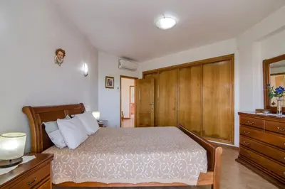 a bedroom with a bed and a wooden cabinet at Villa do Lago in Albufeira