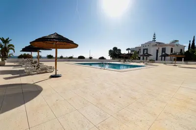 a patio with an umbrella and a swimming pool at Olhos De Água 1BR with Pool, AC and Free Parking in Albufeira