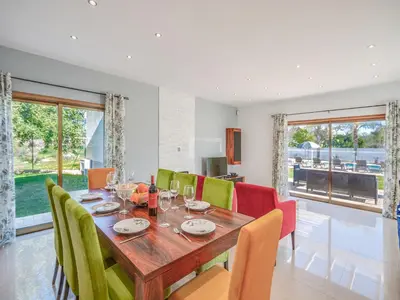 a dining room with a wooden table and colorful chairs at Stunning Luxury Villa Private Pool, Galé Albufeira in Albufeira
