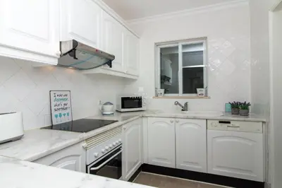 a white kitchen with white cabinets and a sink at Blue Apartment Balaia Space - By Dalma Portuguesa in Albufeira