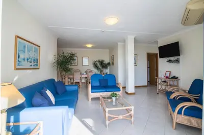 a living room with blue furniture and a flat screen tv at Apartamento no Clube Praia da Oura in Albufeira