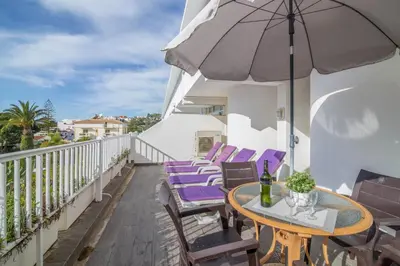 a balcony with purple chairs and a table and an umbrella at Apartamento no Clube Praia da Oura in Albufeira