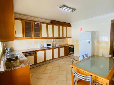 a kitchen with wooden cabinets and a white refrigerator at Rafael by Check-in Portugal in Albufeira