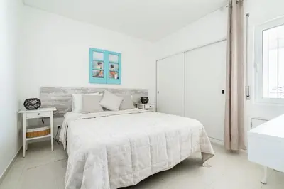 a white bedroom with a large bed and a window at Praia Mar in Quarteira