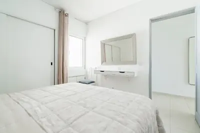 a white bedroom with a bed and a mirror at Praia Mar in Quarteira