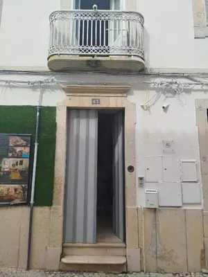 a bedroom with a bed with two chairs and a wall with wallpaper at São Pedro Suite Faro in Faro