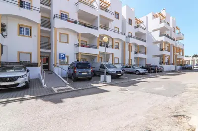 a parking lot with cars parked in front of a building at Casa do Algarve in Albufeira