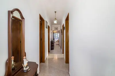 a hallway with white walls and a mirror and a table at Casa Guerreiro in Branqueira