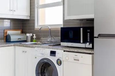 a kitchen with a washing machine and a microwave at Marina Pearl - View to Vilamoura Marina in Vilamoura