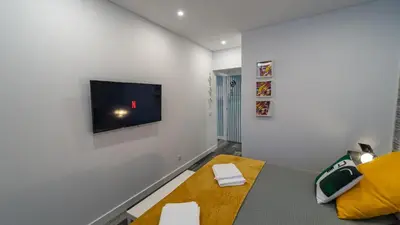 a living room with a tv on a white wall at Plan Be GuestHouse in Faro