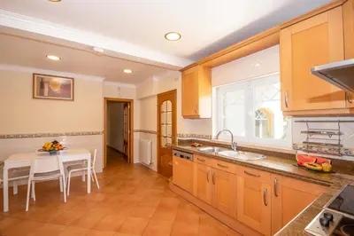 a kitchen with wooden cabinets and a white table and a sink at Villa Samoa by Algarve Vacation in Albufeira