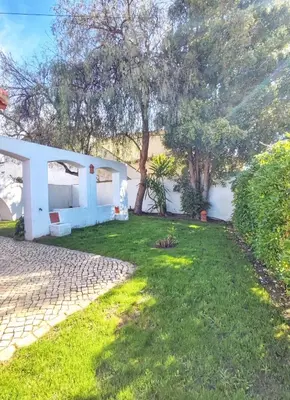 a yard with a white house and trees at Oura Family House in Albufeira