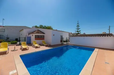 a swimming pool with two chairs and a house at Oura Family House in Albufeira