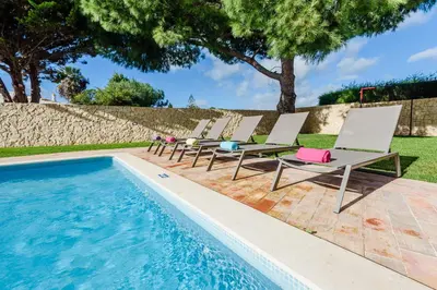 a row of lounge chairs next to a swimming pool at Villa Protea - 5 bedroom, beach, air-con, wifi in Albufeira