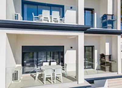 a house with white chairs and a table on the balcony at Correeira Luxury Residence in Albufeira