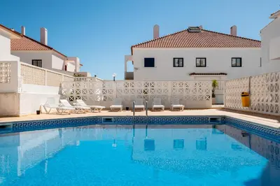 a swimming pool with an umbrella in front of a building at #029 Oura Village by Home Holidays in Albufeira