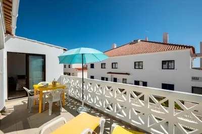 a patio with a table and an umbrella on a balcony at #029 Oura Village by Home Holidays in Albufeira