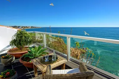 a balcony with a table and chairs and the ocean at Casa Latino - Oceanfront - Luxury & Charming villa- Jacuzzi at Rooftop by DreamvillasAlbufeira in Albufeira