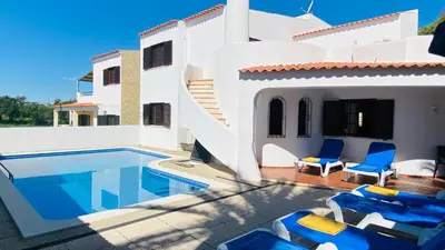 a white house with a swimming pool and blue chairs at Azinheira by Check-in Portugal in Albufeira