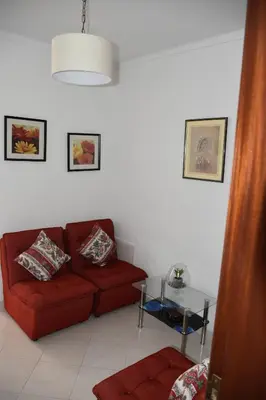 a living room with a red couch and a glass table at Apartamentos Encosta do Mar in Albufeira