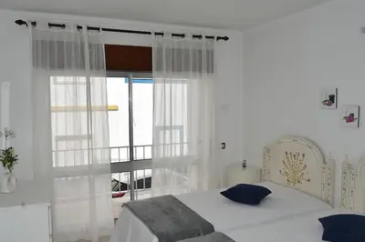 a white bedroom with a bed and a window at Apartamentos Encosta do Mar in Albufeira
