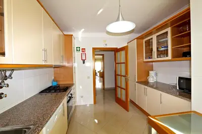 a kitchen with white cabinets and a sink at Vilamoura, Moura Praia in Quarteira