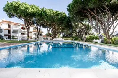 a swimming pool in a villa with trees at Cosy by the pool in Quarteira