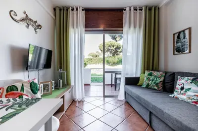 a living room with a couch and a tv at Cosy by the pool in Quarteira