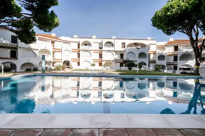 a pool in front of a large building at Cosy by the pool in Quarteira
