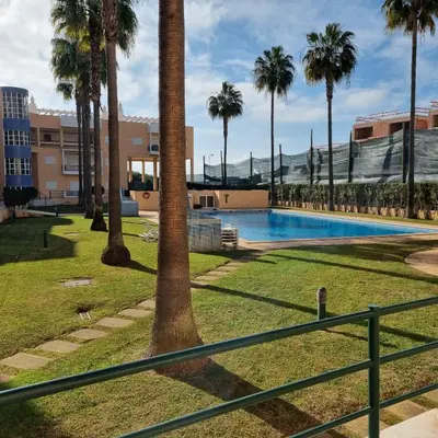 a swimming pool with palm trees and a fence at Vilamoura, Marina Sol T2 in Vilamoura