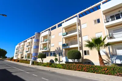 a large apartment building with palm trees and a street at Vilamoura, Marina Sol T2 in Vilamoura