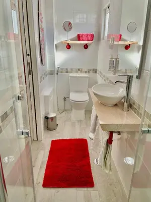 a bathroom with a toilet and a sink and a red rug at Bambus House Blue in Quarteira